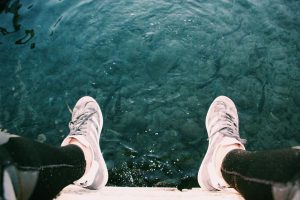 Person Sitting on Cliff Near Water